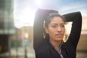 Portrait of young woman stretching, arms behind head